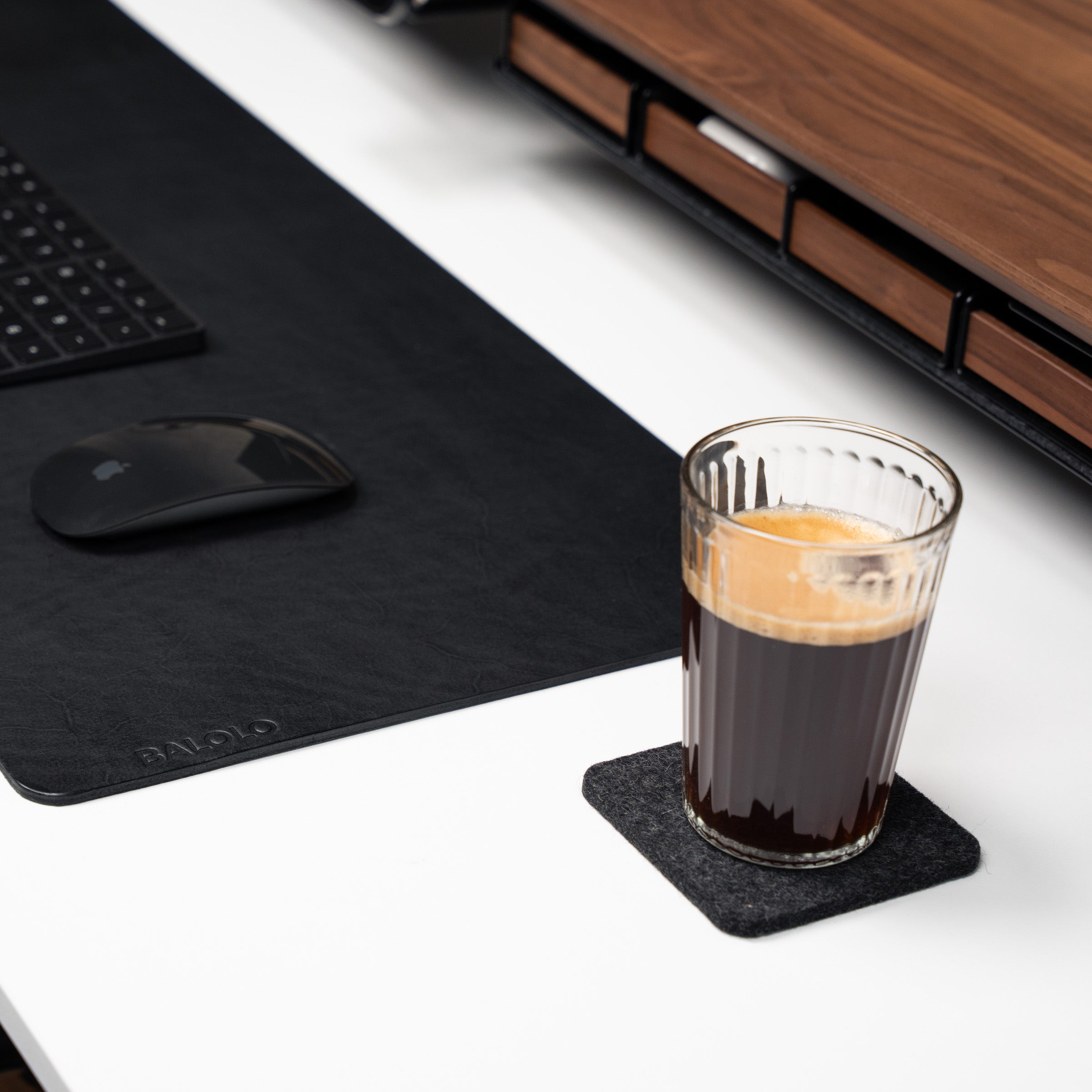 Detailansicht Desk Coaster auf weißem Schreibtisch in Nussbaum Desk Setup. Dargestellt mit Kaffee im Glas.