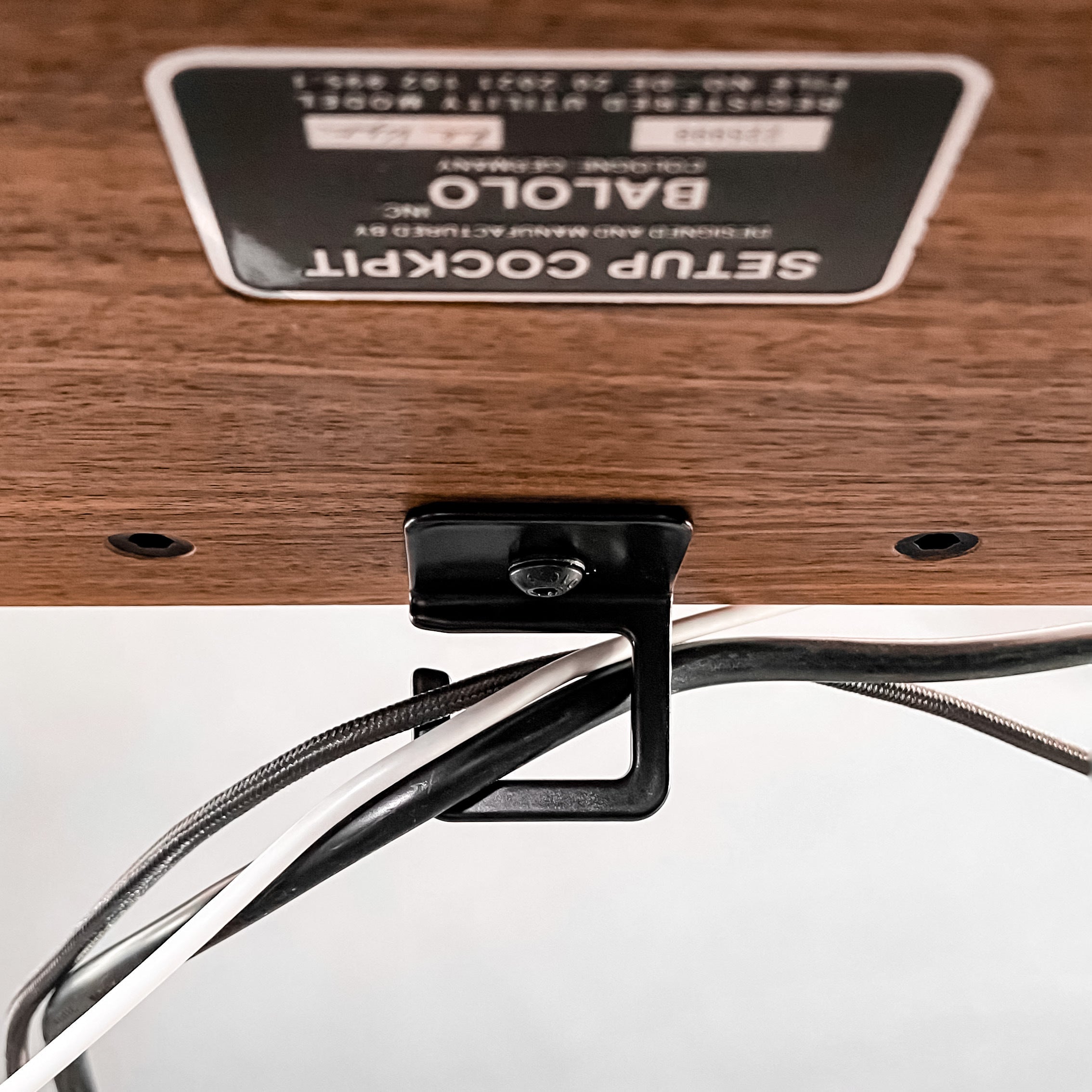 Detailansicht Kabelführung unter dem Setup Cockpit Monitorständer, mit Kabeln die geordnet werden.