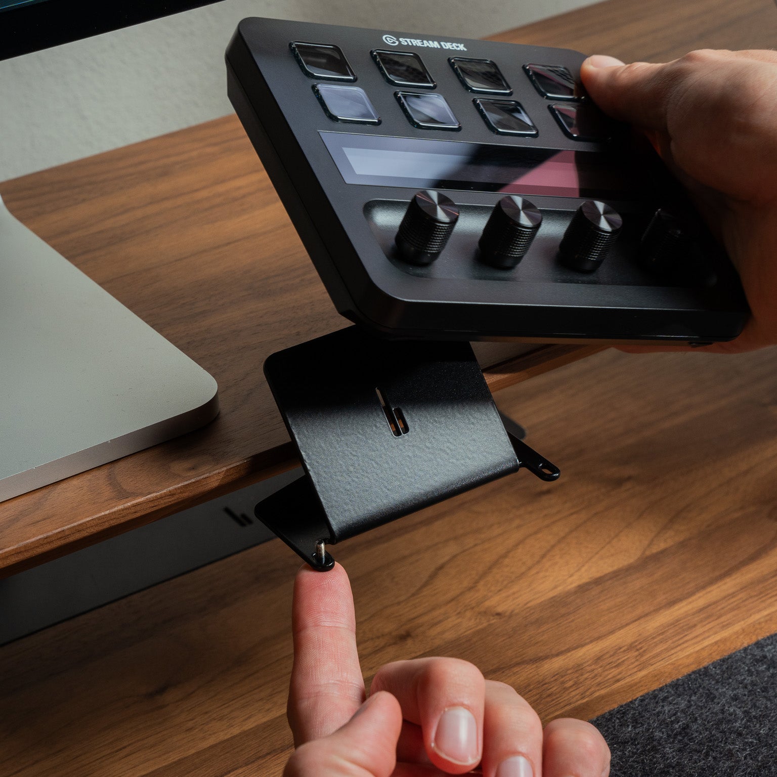 Detailaufnahme vom BALOLO Stream Deck Halter Plus am Setup Cockpit Monitorständer. Elgato Stream Deck Plus wird von einer Hand aus der Halterung genommen. In ästhetischem Office-Setup in Szene gesetzt.