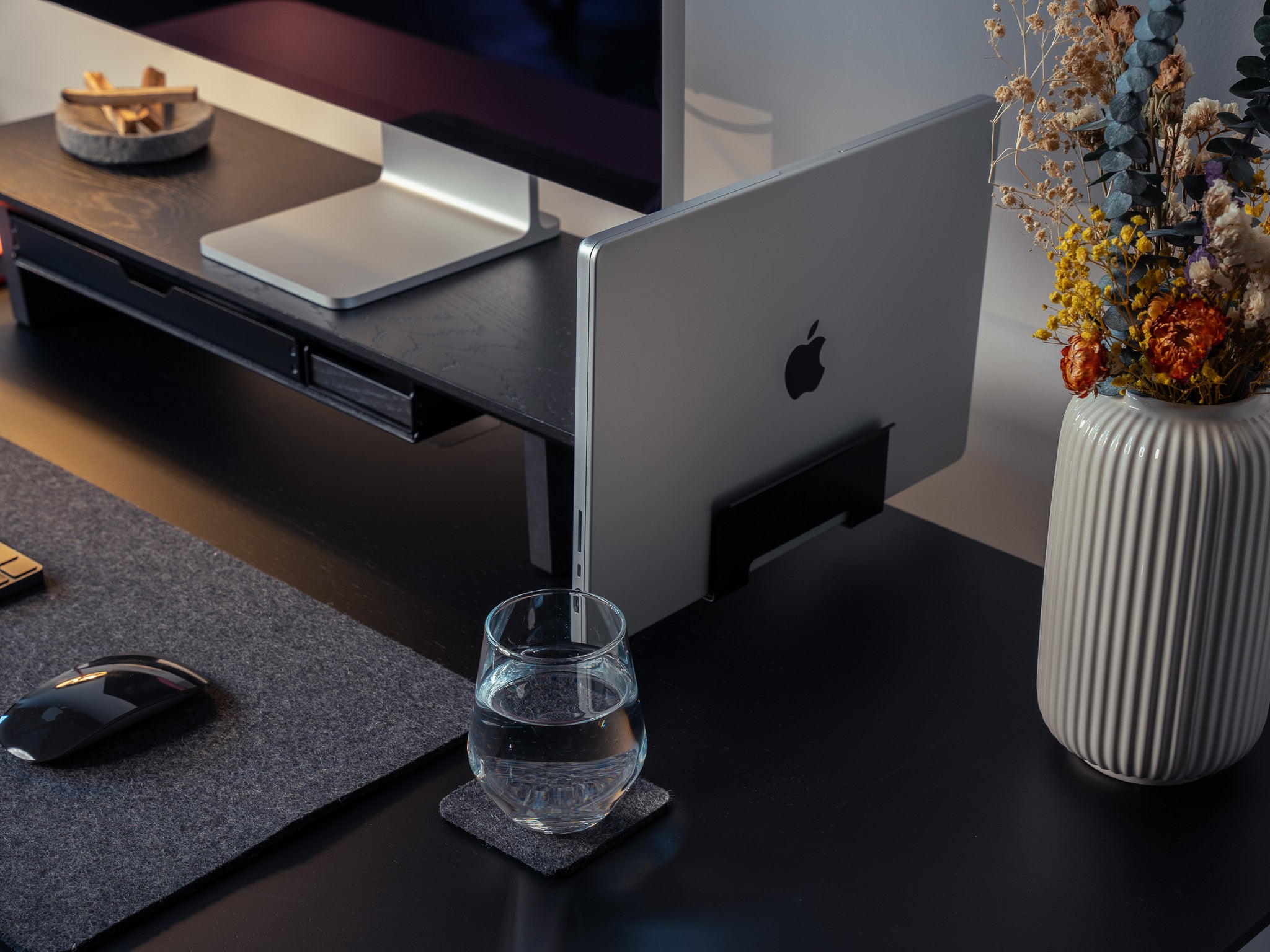 Detailansicht des Laptop Dock mit Macbook am Setup Cockpit Monitorständer Medium. Dargestellt in modernem Office Setting. @expand