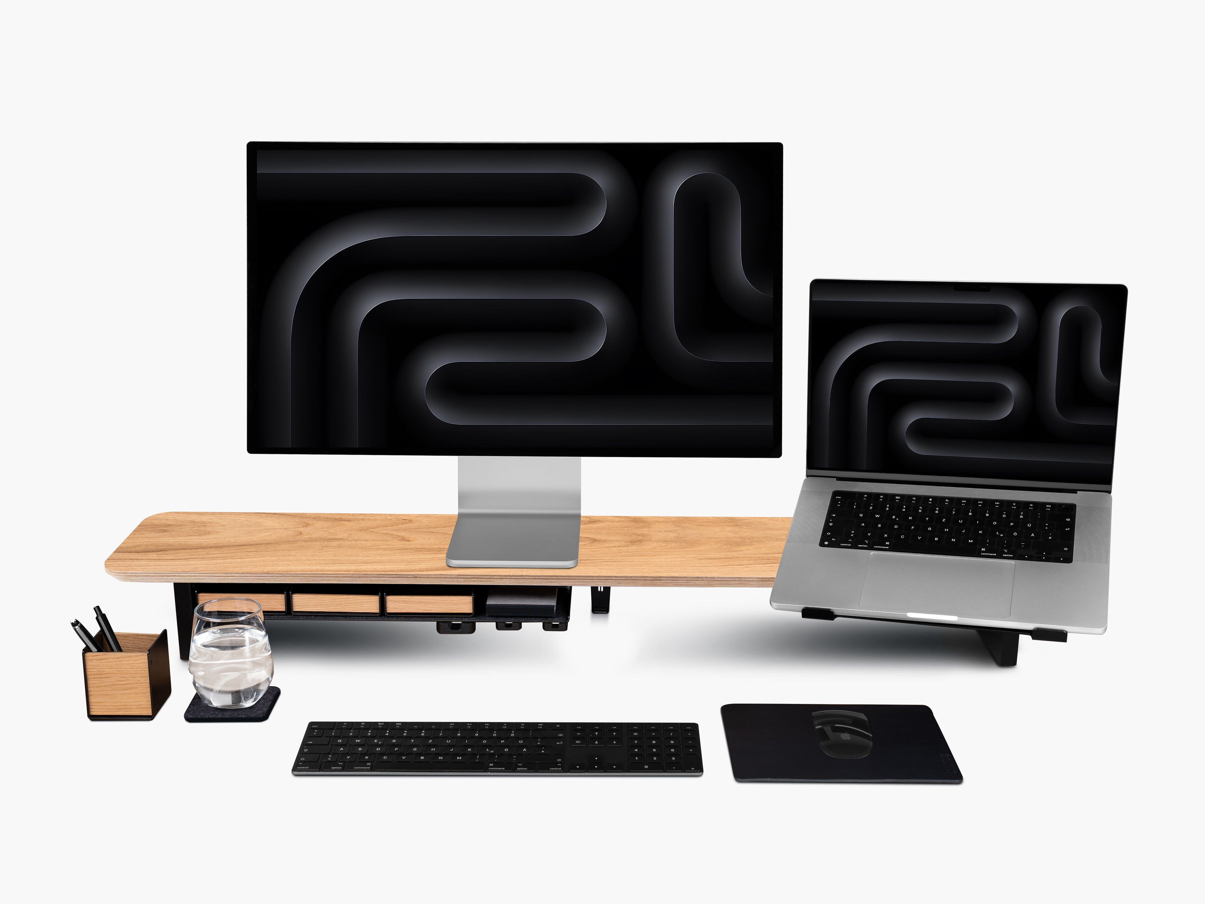 Setup Cockpit Monitorständer aus Eiche mit Anbauteilen: Laptophalter, großes Fach mit Stiftablagen, Kabelmagnete, Mauspad Leder, Stifthalter und Desk Coaster. Abgebildet mit Apple Studio Display, Tastatur und Maus.