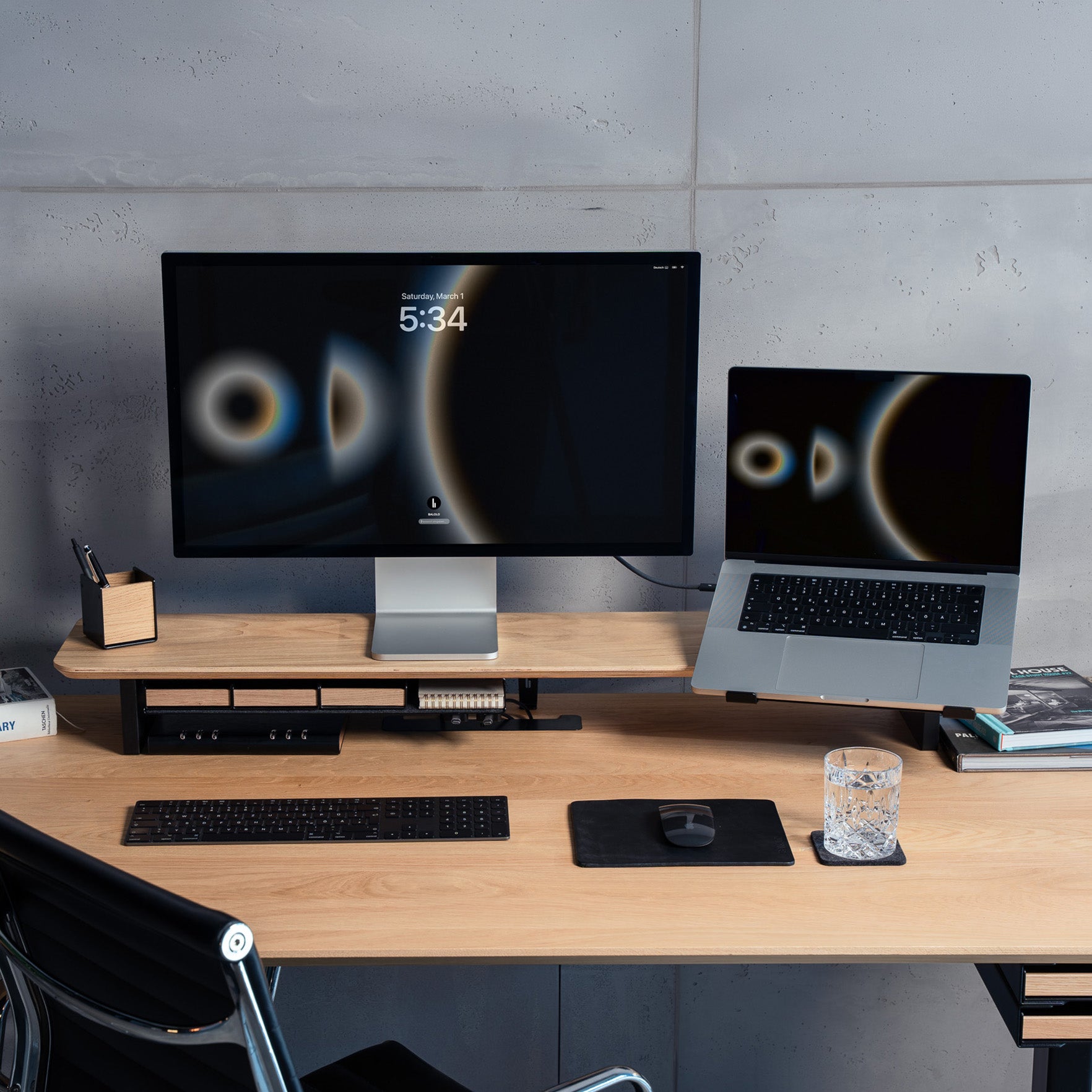 Totalaufnahme des Setup Cockpit Monitorständers aus Eiche, ausgestattet mit Laptophalter, Macbook, Apple Studio Display, Fächern und Ablagen. In modernem Büro.