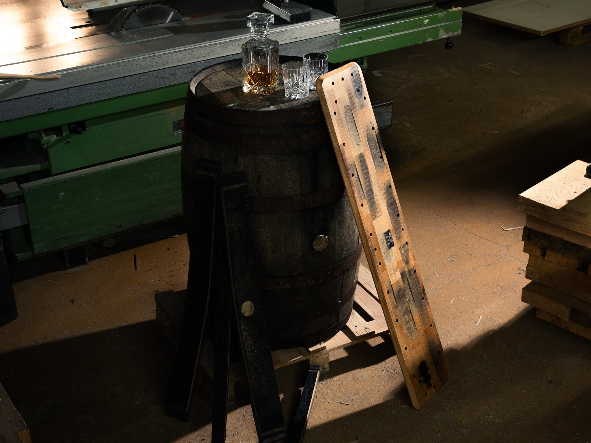 Beauty Shot der Whiskey Barrel Edition inszeniert in nostalgischer Werkstatt, angelehnt an ein Whiskyfass mit Gläsern und Karaffe.