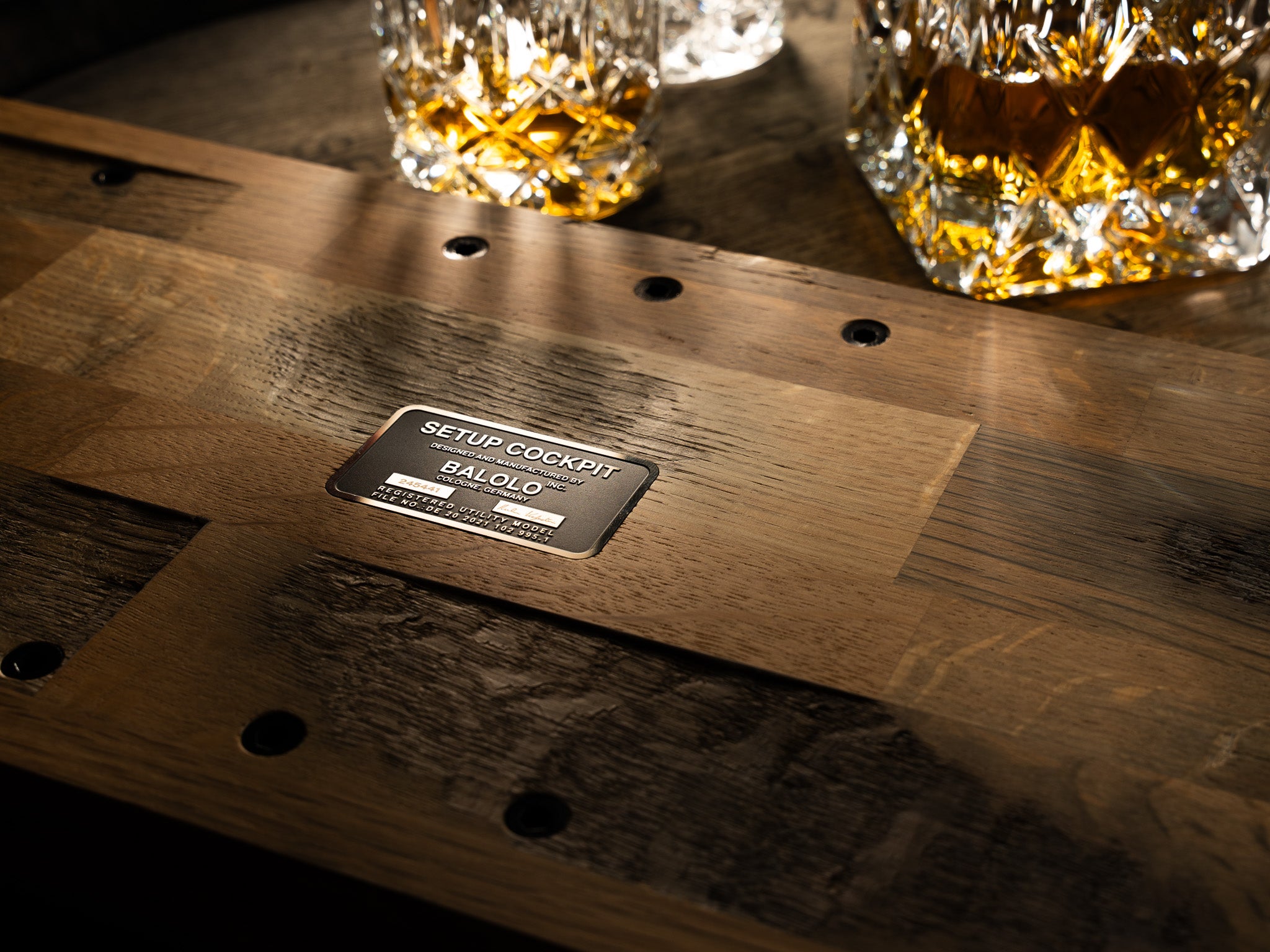 Detailaufnahme der Unterseite des BALOLO Setup Cockpit Monitorständer Whiskey Barrel Edition. Fokus auf Plakette.