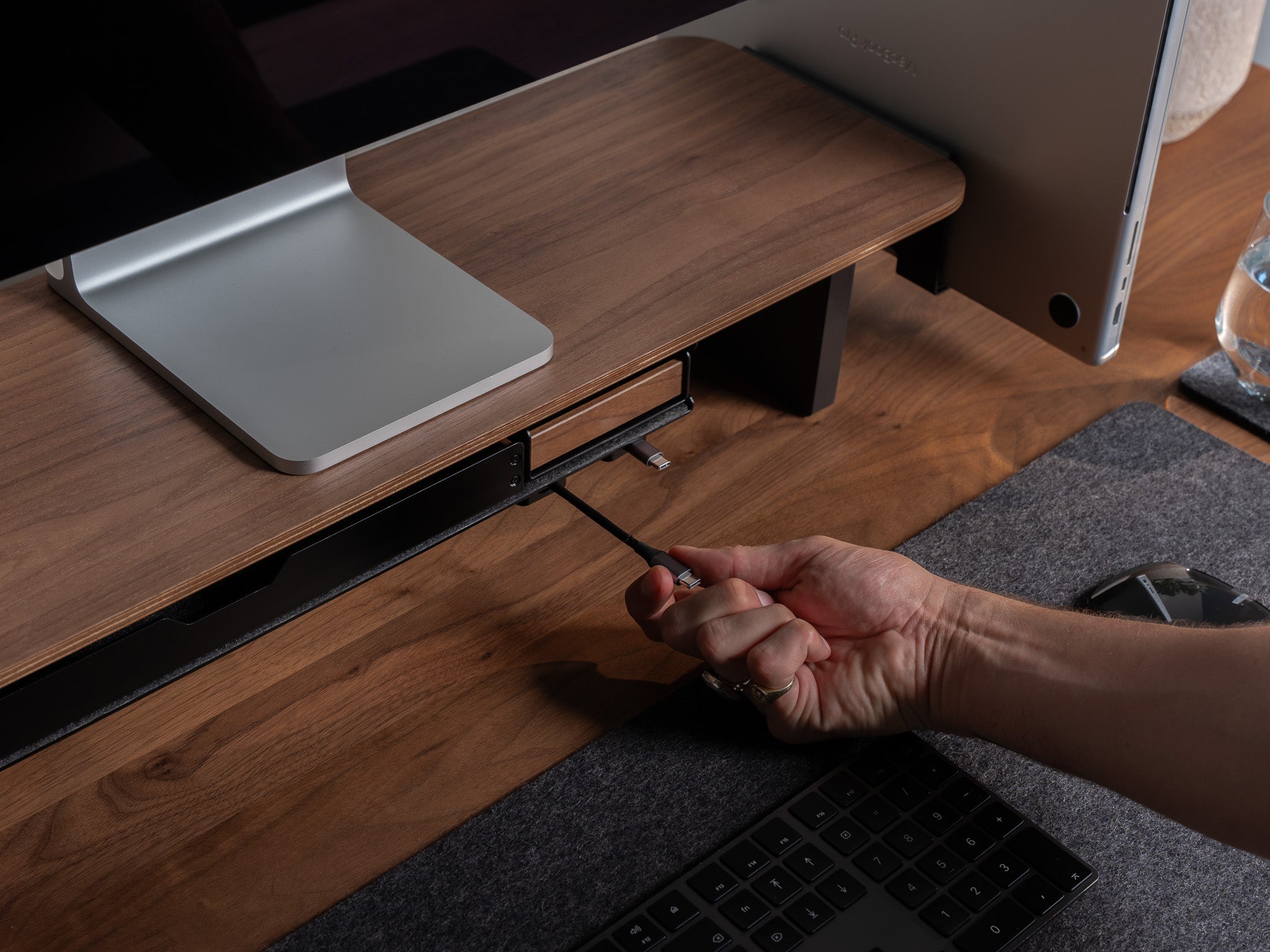 Detailansicht Kabelmagnete an großem Fach unter dem Setup Cockpit aus Nussbaum. Fokus auf Ladekabel, dass durch Kabelmagnete befestigt ist. @expand