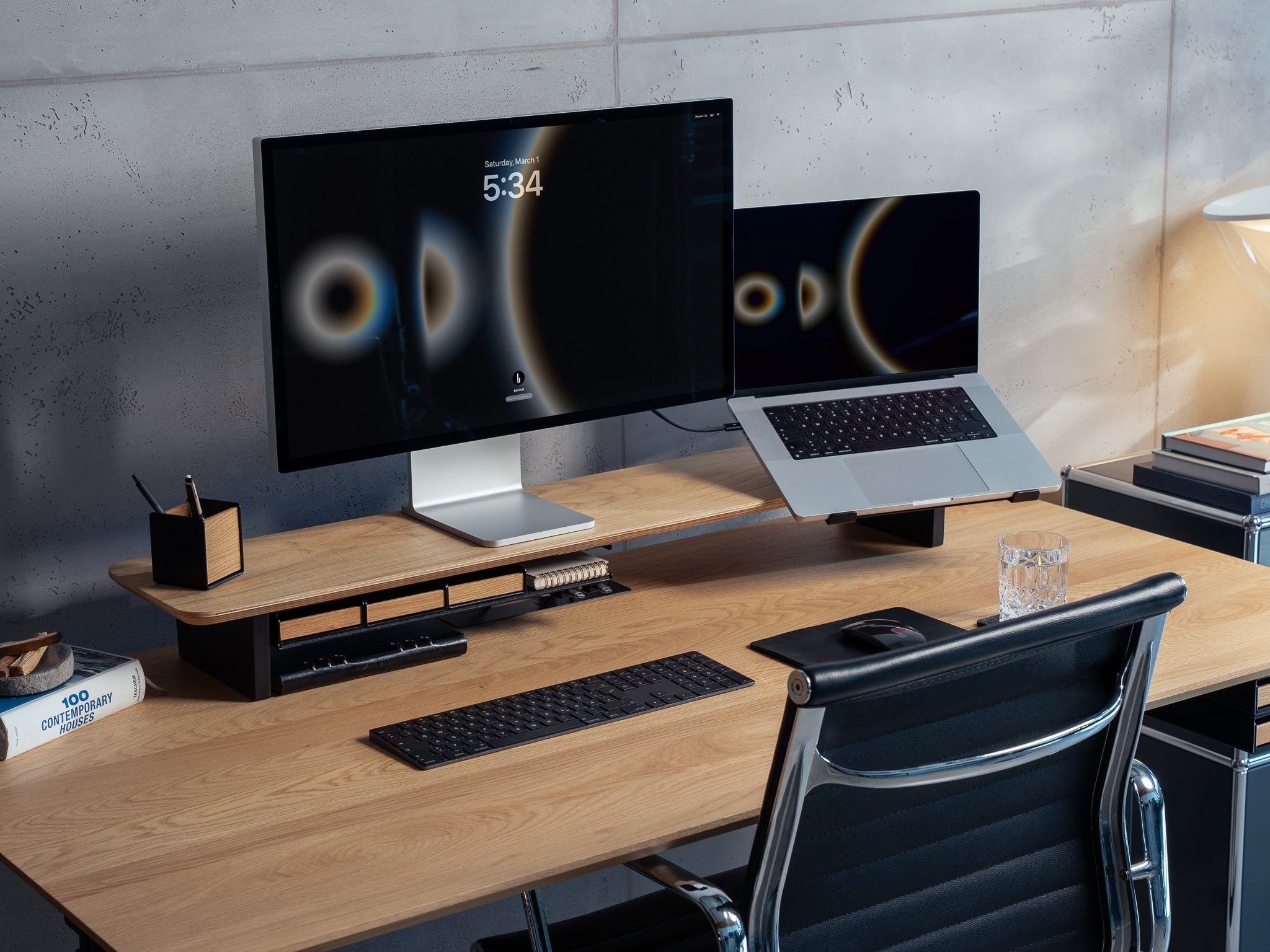 Setup Cockpit Monitorständer aus Eiche auf Schreibtisch aus Eiche. Im Setup mit Anbauteilen: Laptophalter, großes Fach mit Stiftablagen, Kabelmagnete, Mauspad Leder, Stifthalter und Desk Coaster. Dargestellt in modernem Office Setting. @expand
