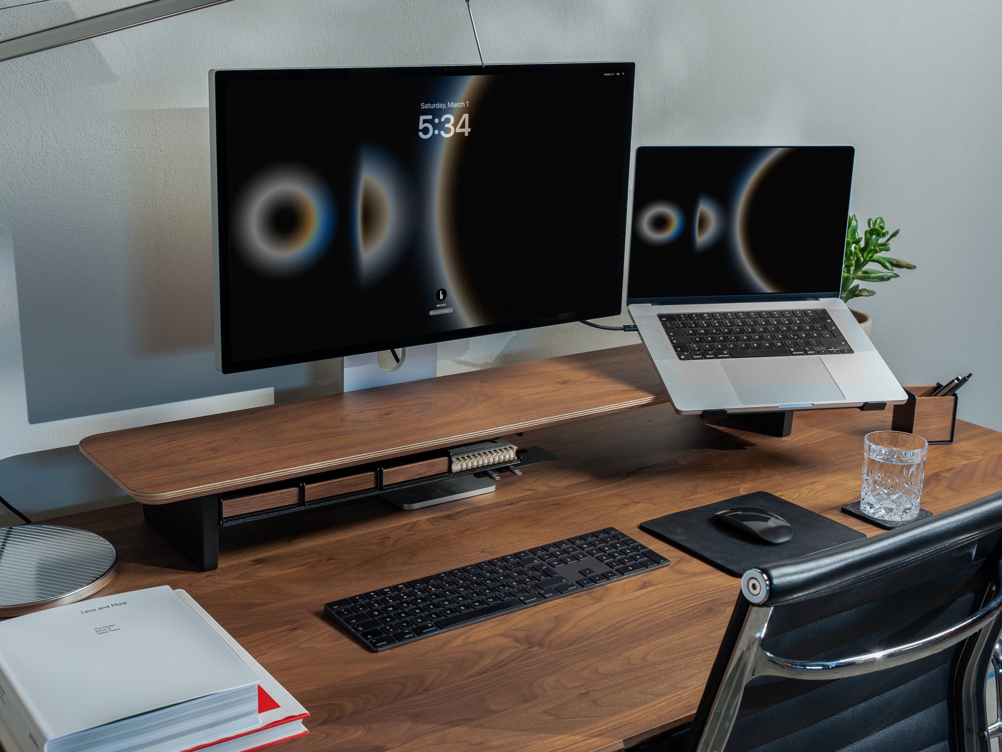 Setup Cockpit Monitorständer aus Nussbaum auf einem Schreibtisch aus Nussbaum mit Anbauteilen: Laptophalter, großes Fach, Stiftablagen, Mauspad Leder, Stifthalter. Abgebildet in modernem Office Setup. @expand