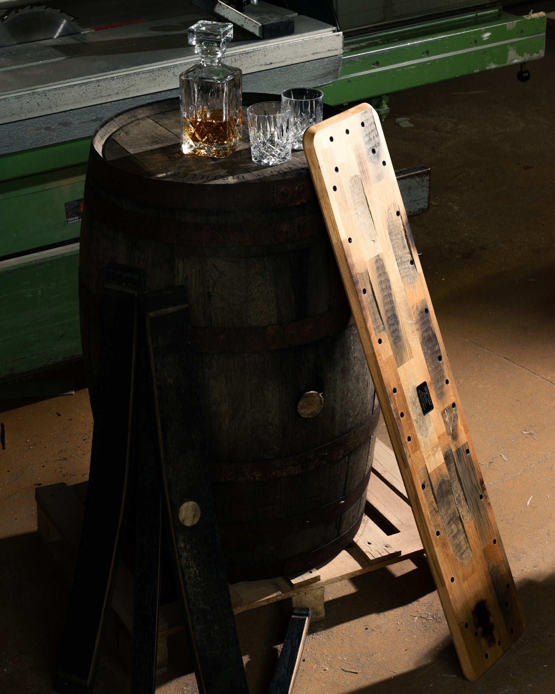 Beauty Shot der Whiskey Barrel Edition inszeniert in nostalgischer Werkstatt, angelehnt an ein Whiskyfass mit Gläsern und Karaffe.